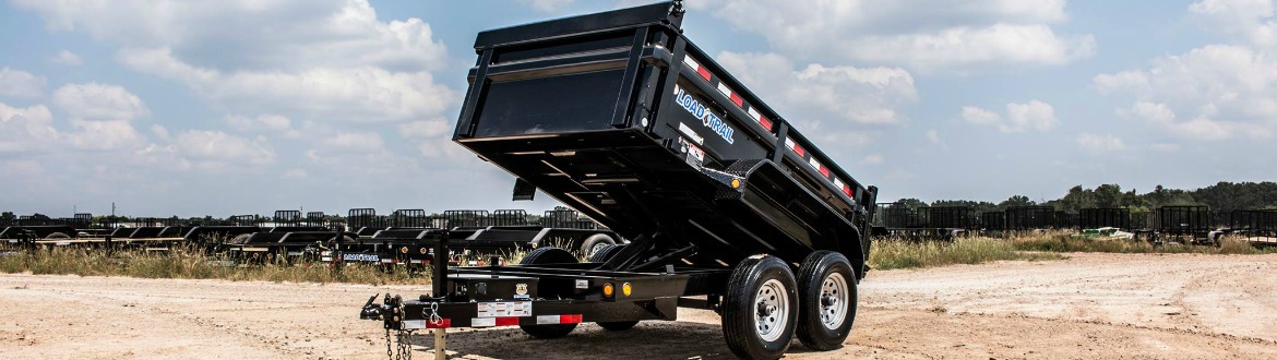 Dump trailer sitting in a dirt lot outside with more trailers in the background.